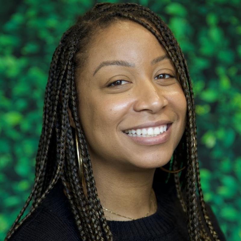 A photo of Brianna Harvey wearing a black shirt with a green background.
